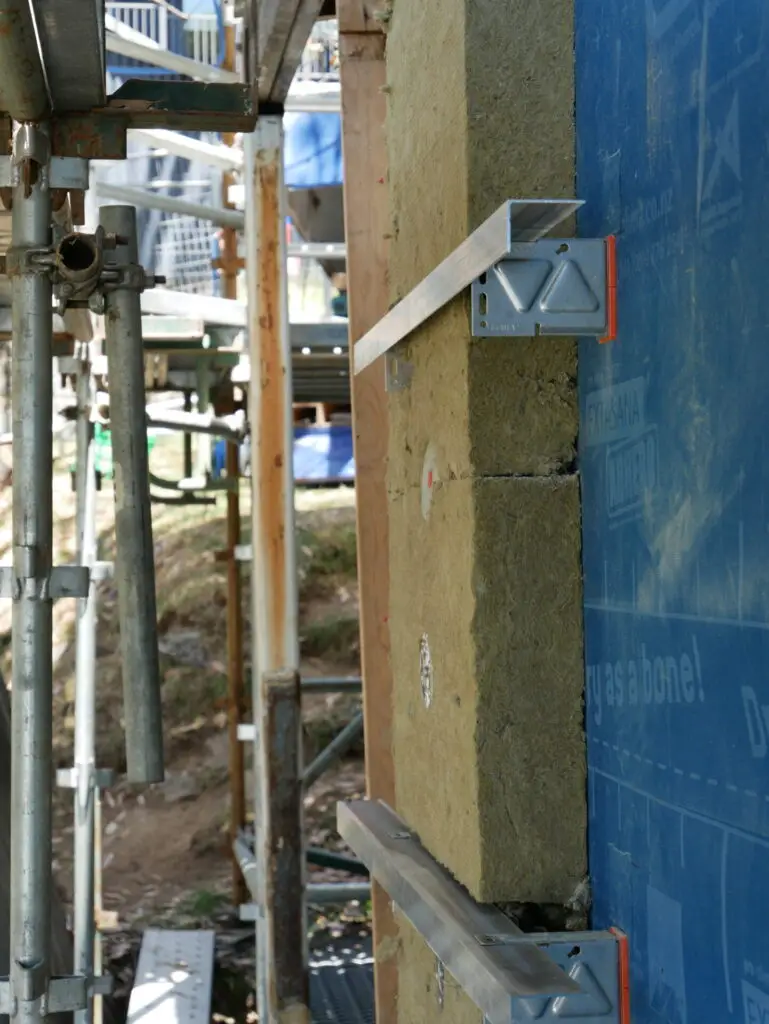 Stainless steel CROSSFIX bracket installed over rockwool insulation with façade fasteners on site.